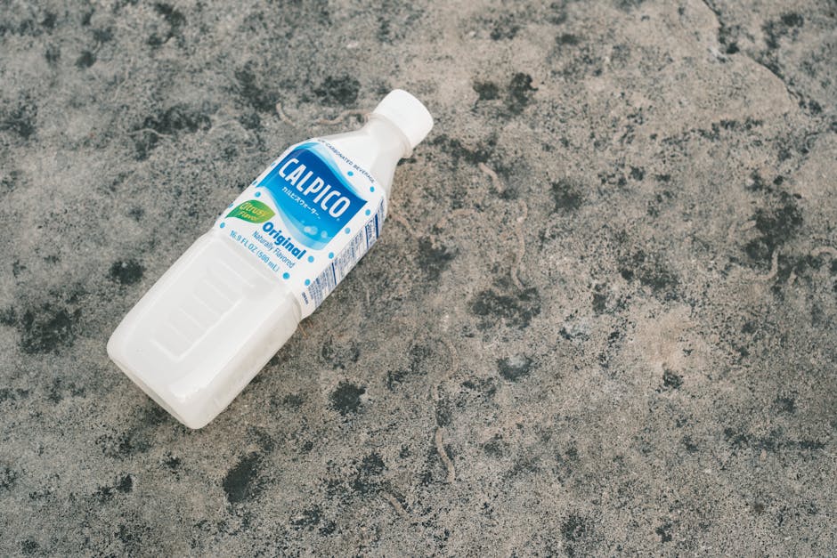 A Calpico soft drink bottle captured on a rustic concrete background in daylight.