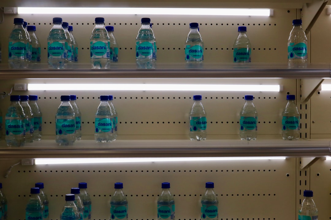 Bottled water is stacked on illuminated shelves.