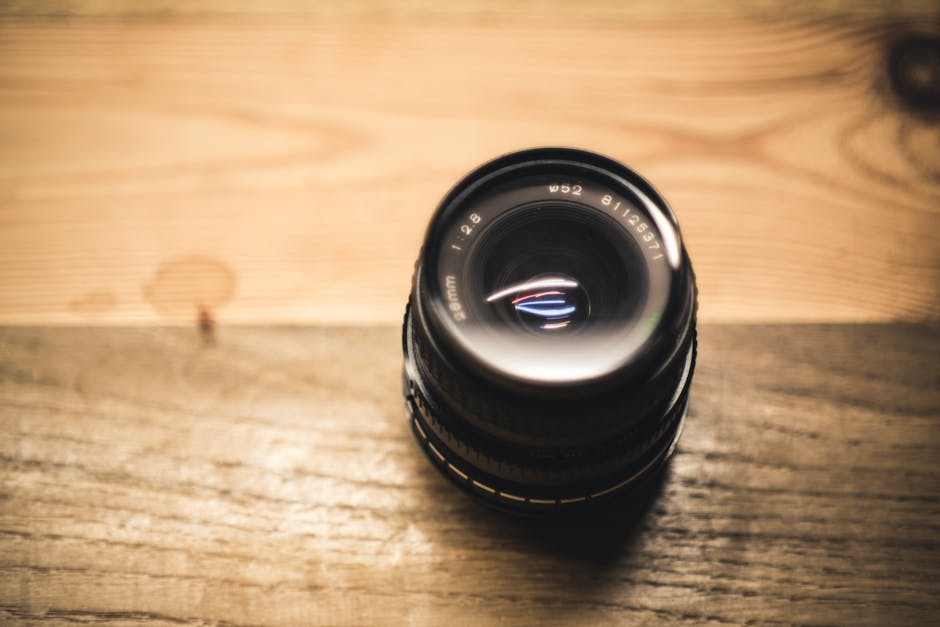 Detailed shot of a camera lens resting on a wooden table, highlighting equipment precision.