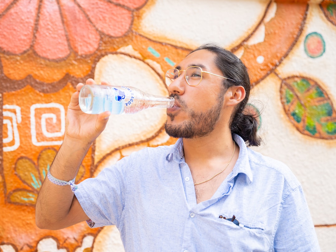 a man drinking water from a plastic bottle