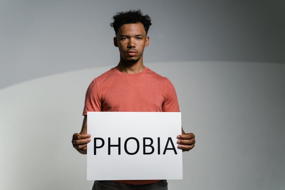 A man holding a sign that reads 'PHOBIA' symbolizes awareness and feelings of fear and anxiety.