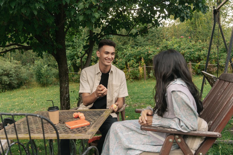 A couple enjoying a casual conversation with coffee and apples in a tranquil garden.