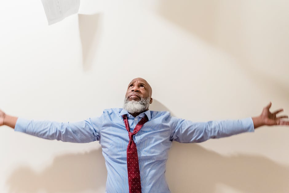 A frustrated businessman with arms outstretched, expressing vulnerability and stress indoors.