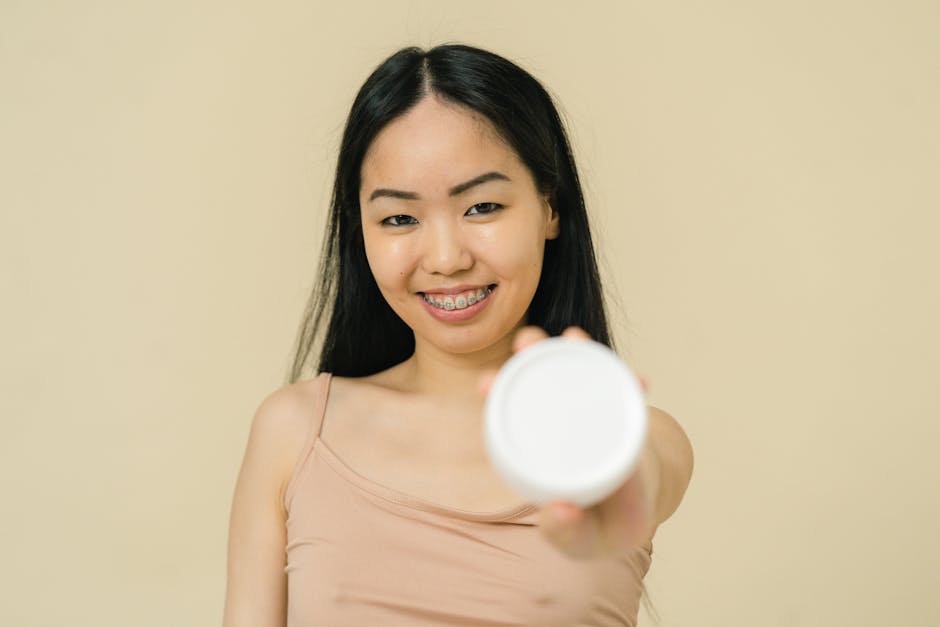 Portrait of a young woman with braces holding a cosmetic product jar with a smile.