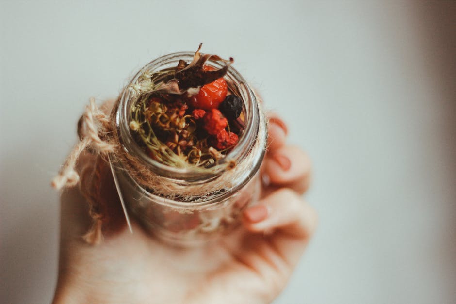Delicate hand holding a rustic jar filled with dried herbs and berries, perfect for organic and herbal themes.