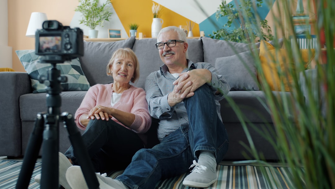 Elderly couple smiling at camera in-home video camera setup.