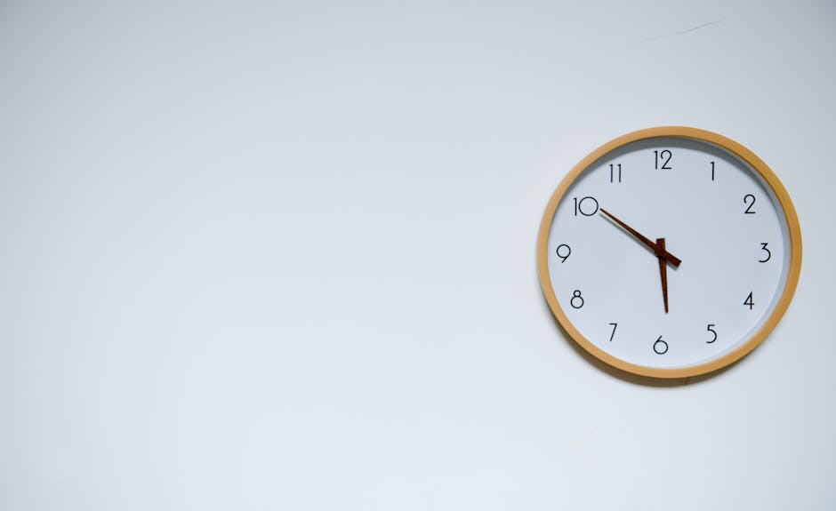 Simple wall clock with wooden frame against a white background, showing the time 10:10.