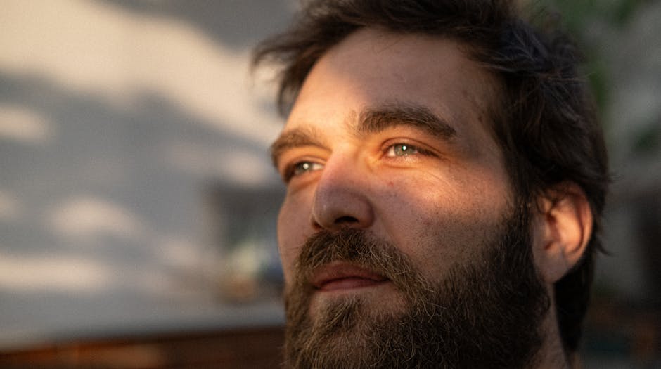 Close-up portrait of a man basking in sunlight, creating a warm and introspective mood.