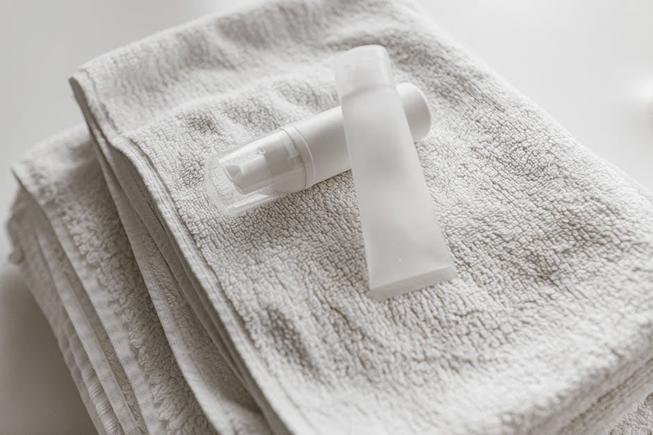 Clean and simple display of white skincare bottles on a towel, perfect for self-care themes.