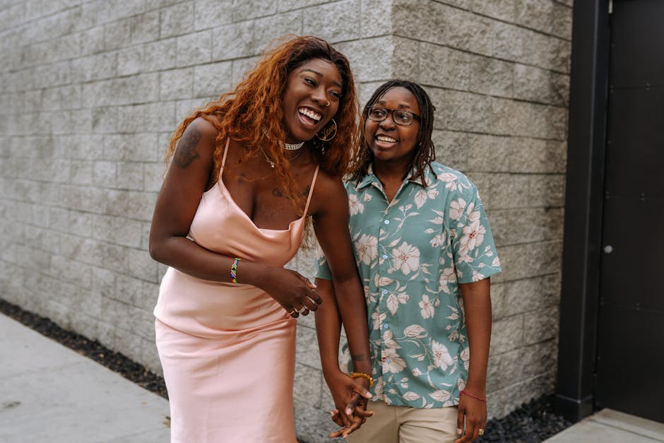 Happy couple standing outdoors, laughing and holding hands, showcasing love and joy.