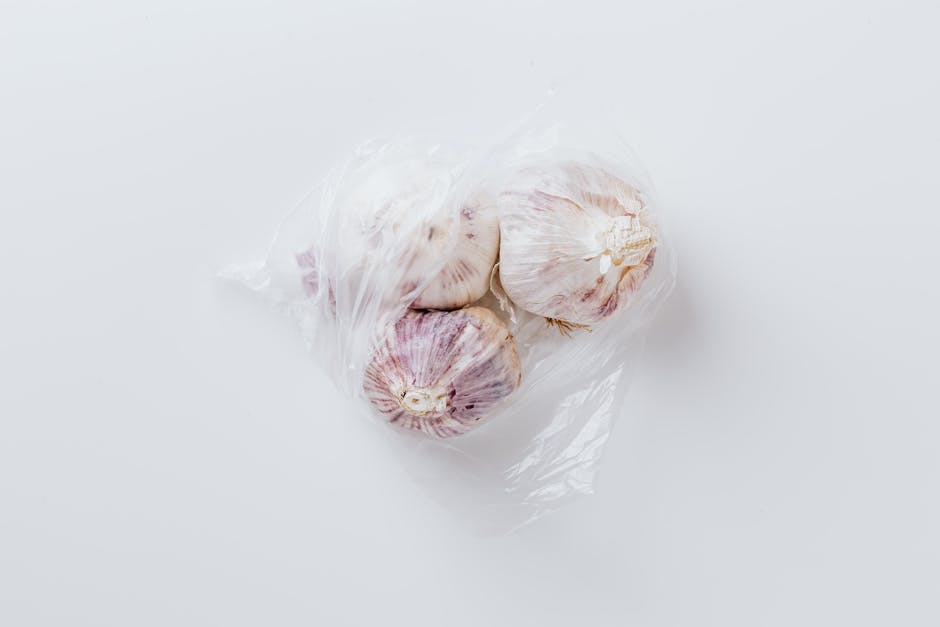 Close-up of fresh garlic bulbs in clear plastic bag, perfect for food photography.