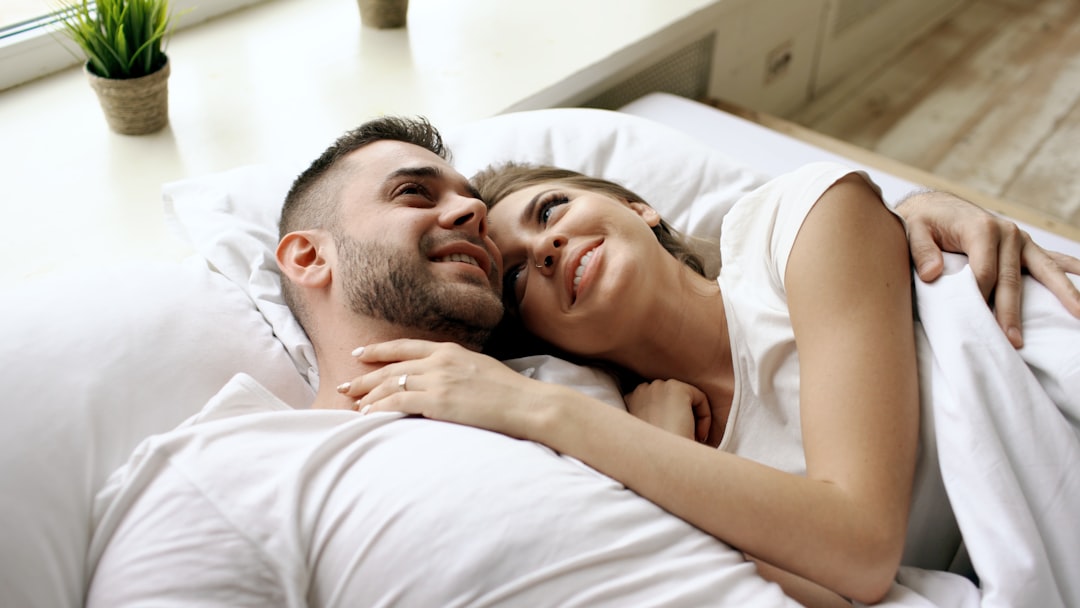 A couple lying in bed, smiling at each other.