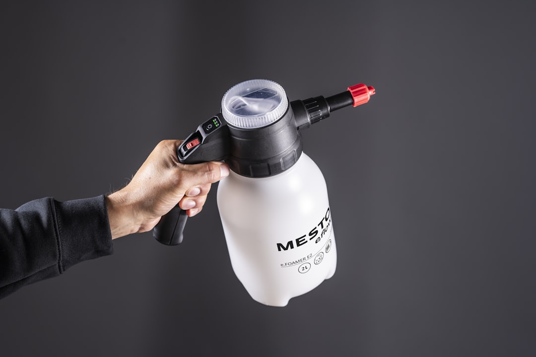 A hand holds a white pump sprayer.