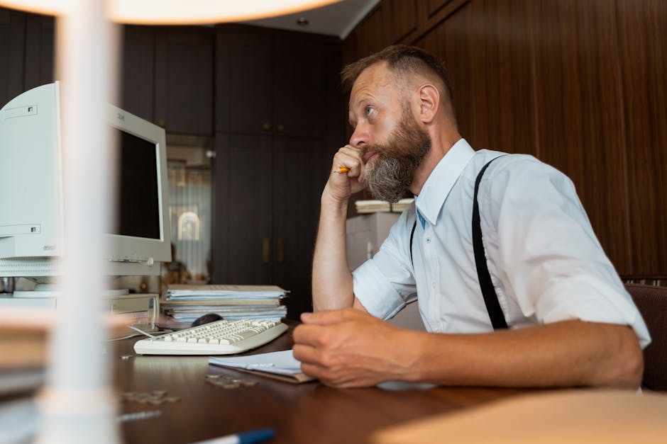 Businessman thinking critically while sitting at his office desk. Side view.